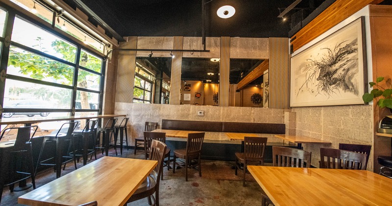 Interior with wooden furniture, large windows and an abstract painting on the wall