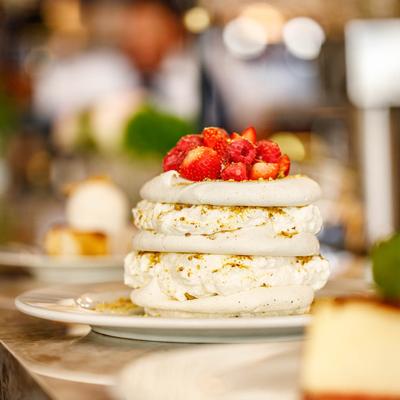 A layered meringue-based dessert with pistachios, topped with berries.