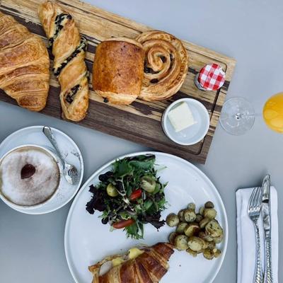 Croissant sandwich with vegetables with cappuccino and pastries on the side