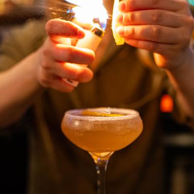 Bartender burning a citrus cocktail garnish