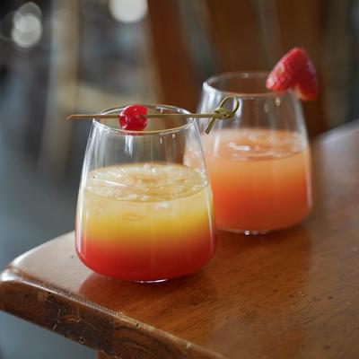 Tequila Sunrise garnished with a cherry, and Grapefruit Mimosa garnished with a strawberry.