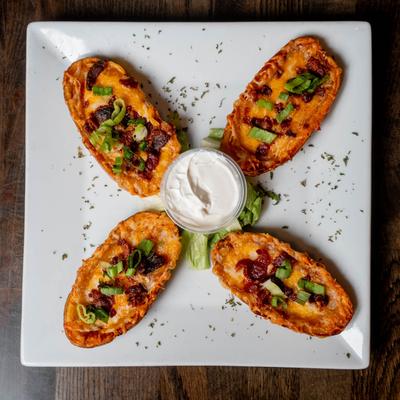 Potato skins with bacon bits, scallions, and a cup of sour cream.