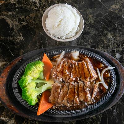 Beef Teriyaki served on a sizzling plate with a side of white rice and steamed vegetables.