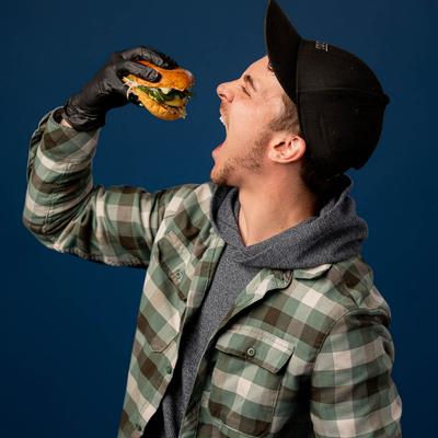A person holding up a burger to their open mouth.