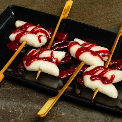 Spicy rice cakes on skewers drizzled with sauce.