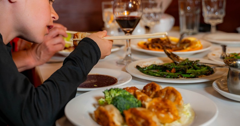 People dining at a table with multiple dishes and wine