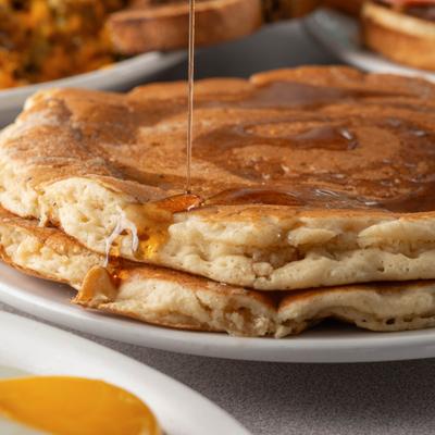 Syrup drizzling over stacked pancakes.