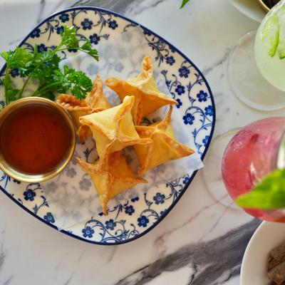 Plate of crab rangoons served with a dipping sauce.