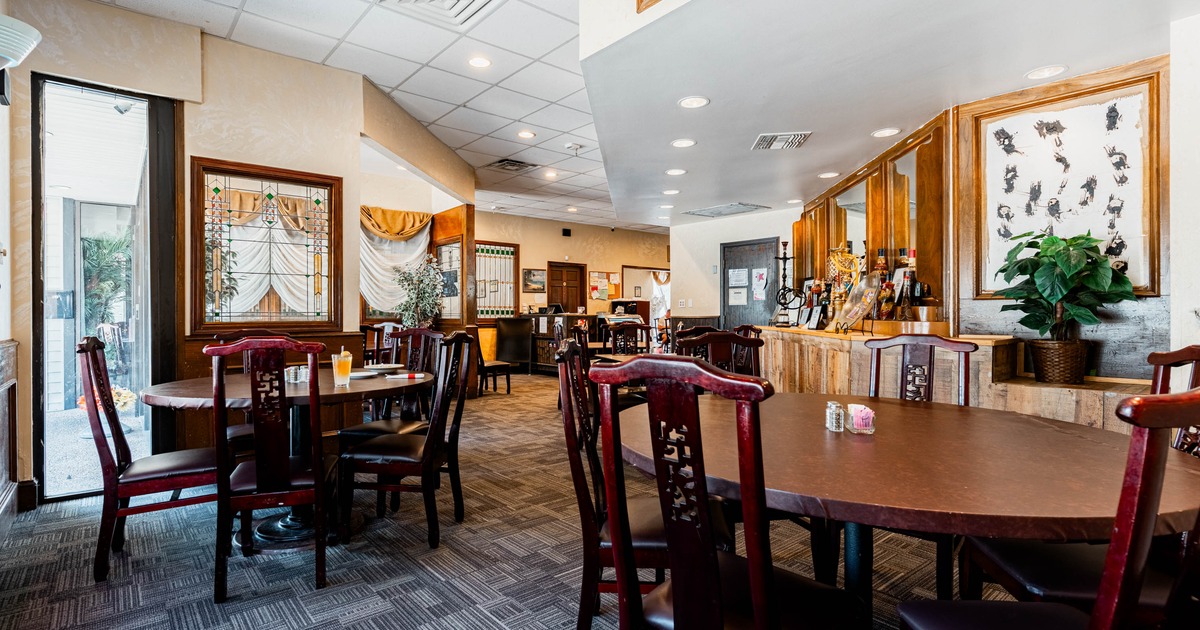 Interior of a restaurant with wooden tables and chairs, stained glass windows