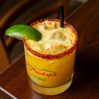 Mango mezcalita in a chili-rimmed glass, garnished with a lime wedge.