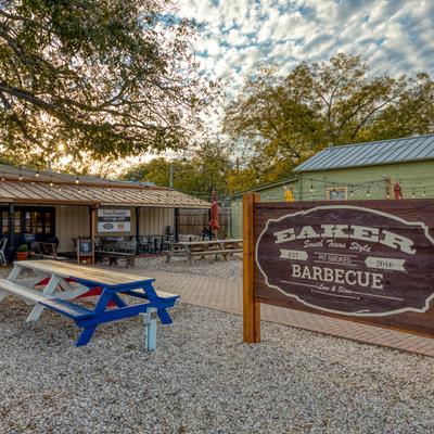 Outdoor seating space with the Eaker Barbecue board sign