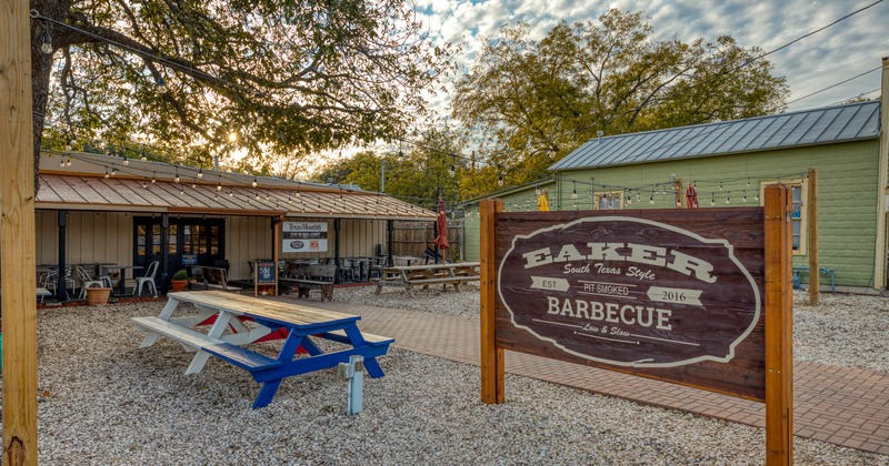 Outdoor seating space with the Eaker Barbecue board sign