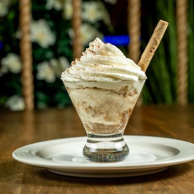 Tiramisu Cappuccino topped with whipped cream and a wafer stick.