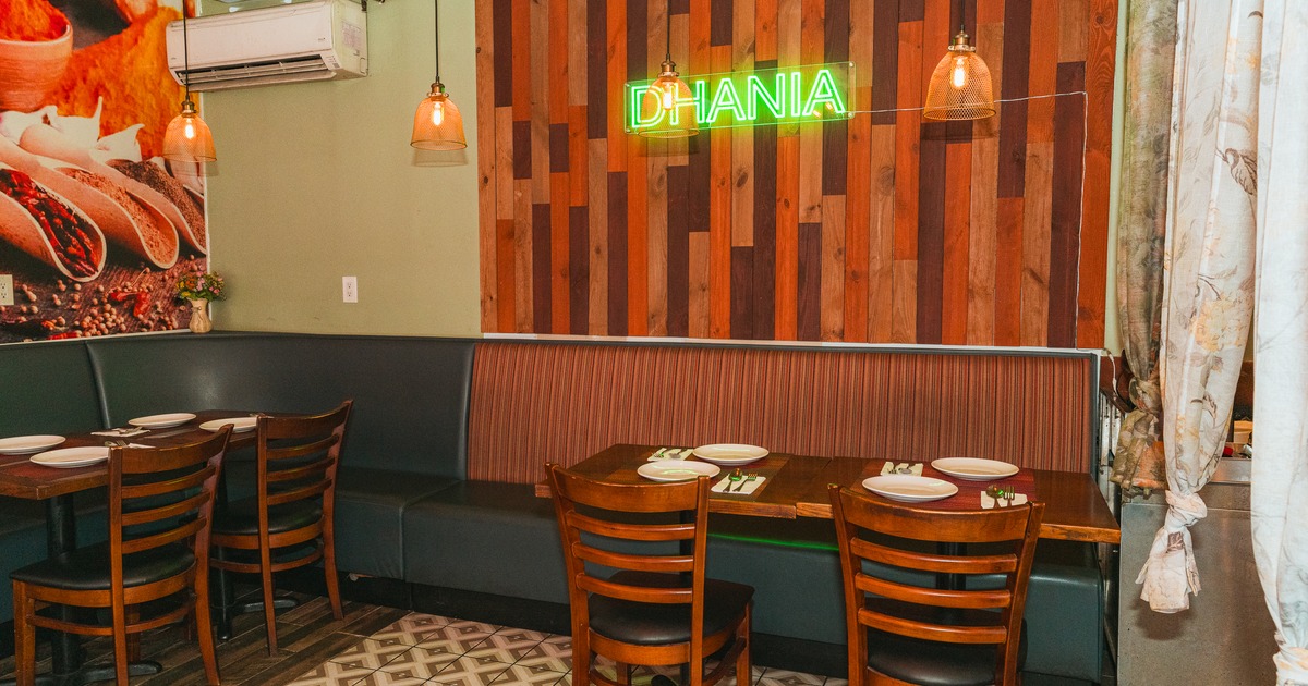 Dining area - wooden chairs and tables set with plates; pendant lighting.