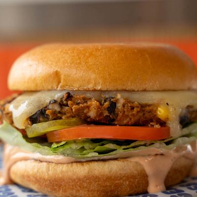 Veggie burger with lettuce, tomato, pickles, and melted cheese.