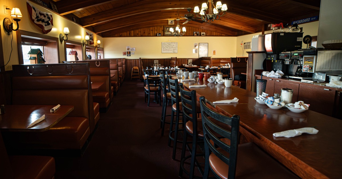 Inside, wooden furniture and decor, featuring booths and a counter with chairs