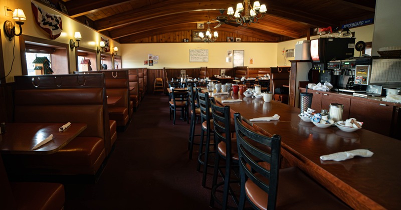 Inside, wooden furniture and decor, featuring booths and a counter with chairs