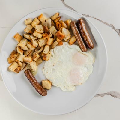 Two fried eggs served  with home fries and sausage links.