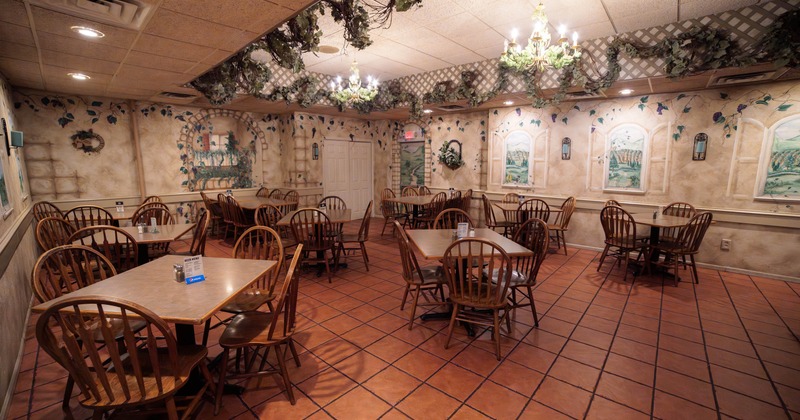 Interior view of a restaurant featuring wooden tables and chairs on a terracotta tiled floor