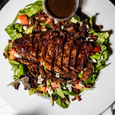 Steak Salad topped with a tender blackened NY Strip Steak.