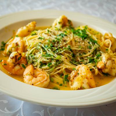 Shrimp scampi served over a bed of pasta, topped with fresh herbs.