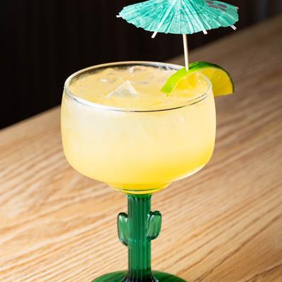 Yellow Margarita garnished with lime and a blue cocktail umbrella.