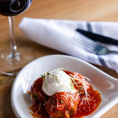 Meatballs dish with a glass of red wine.