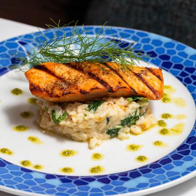Grilled salmon served atop creamy spinach risotto, garnished with fresh dill.