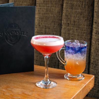 Two cocktails served on the table alongside a restaurant's menu.