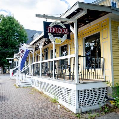 Exterior of The Local restaurant with a yellow facade and outdoor seating.