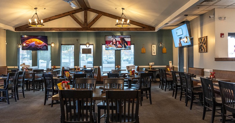 Interior, dining tables ready to receive guests, TVs on the walls