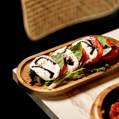 Slices of fresh mozzarella, tomato, and basil drizzled with dark balsamic glaze.