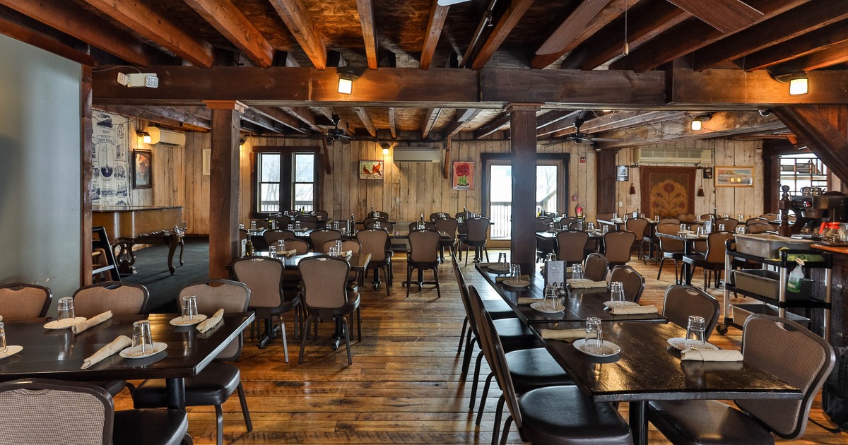 Restaurant interior with wooden beams, tables, and chairs neatly arranged