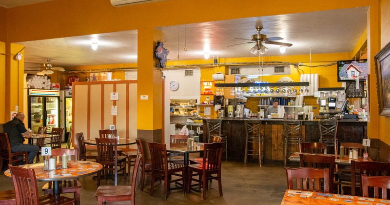 Interior, dining area with a seated guest and the order counter with a staff