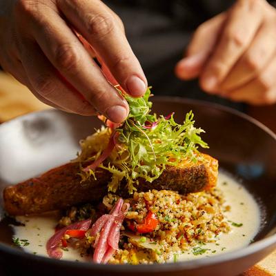 Crispy salmon fillet, with quinoa, white butter sauce, sweet peppers, onion, and pomegranate.