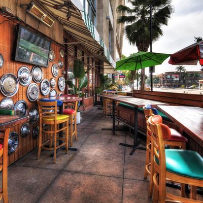 Outdoor seating with colorful chairs and tables, hubcap decor, and a TV on a wall