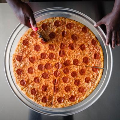 Hands cutting the pepperoni pizza.