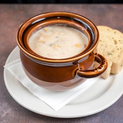 Bowl of creamy clam chowder served with a piece of bread.
