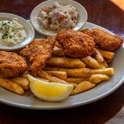 Breaded Arctic cod and fries, served with coleslaw, tartar sauce, and lemon wedge.