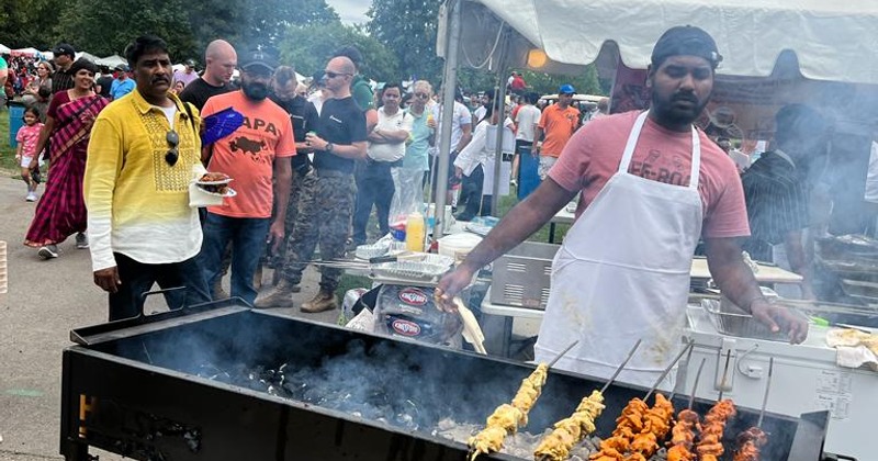 Outdoors, an employee preparing BBQ for people