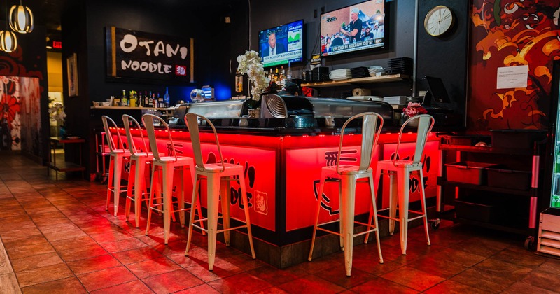 Interior of a restaurant with a red-lit bar and tall white stools