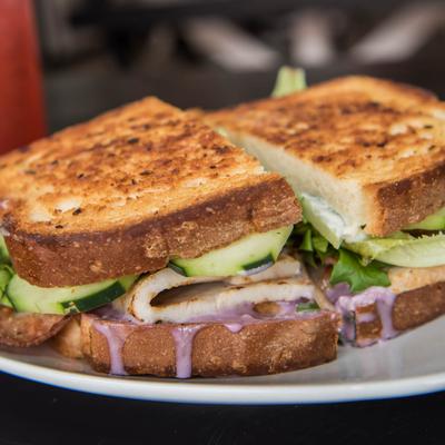 Turkey Huckleberry sandwich, with bacon, field greens, mayo, cream cheese, and cucumber.