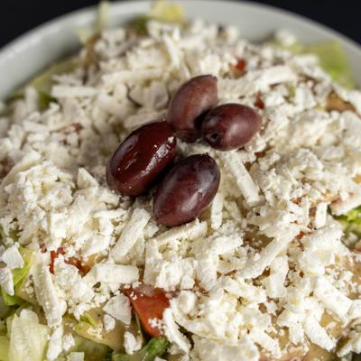 Greek salad topped with shredded feta cheese and kalamata olives.
