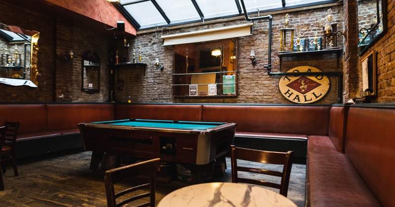 Interior,  decorated brick wall, pool table, leather banquette seating