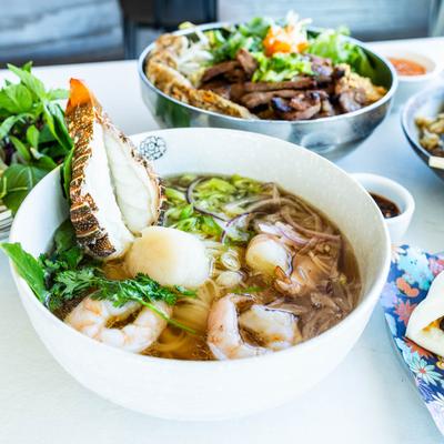 Lobster pho bowl with assorted dishes on a table
