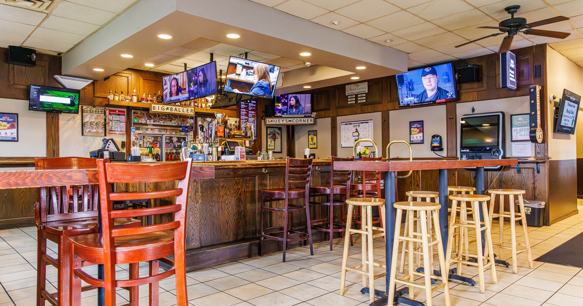 Interior of a bar with wooden furniture, multiple televisions