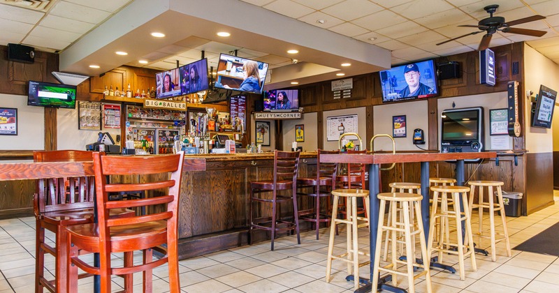 Interior of a bar with wooden furniture, multiple televisions