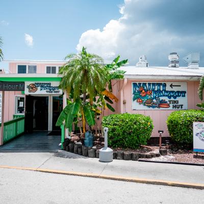Nauti Parrot Tiki Hut exterior with signage and palm trees.