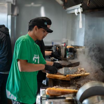 Kitchen staff preparing sandwiches on the grill.