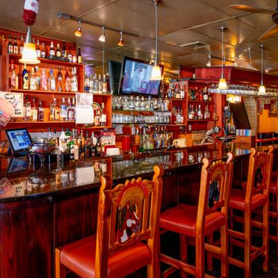 Bar interior with wooden stools and liquor shelves.